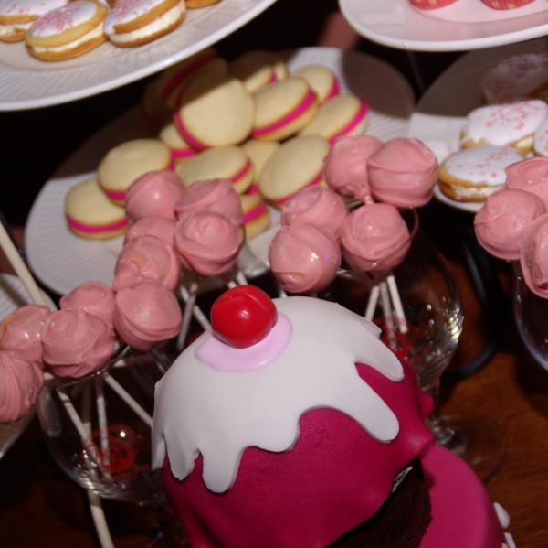 baklava cakepops en whoopie pies met roze marsepeinvulling op de voorgrond: aansnijtaartje van chocolatemudcake in de vorm van een cupcake