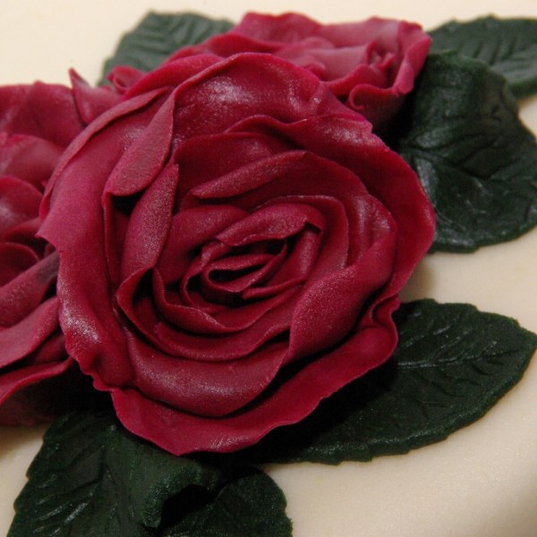 ivoorkleurige bruidstaart met strikken en donkerrode rozen rotterdam nesselande TAART & kUNST